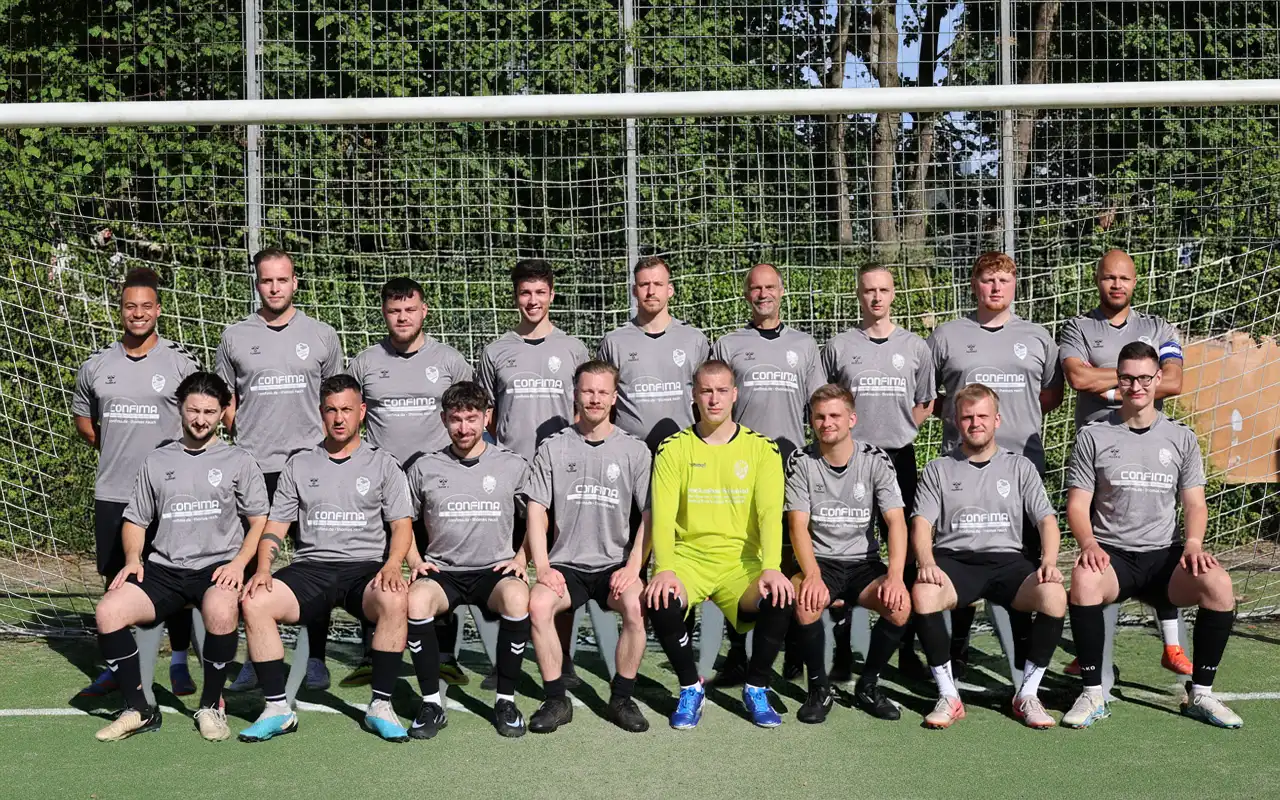 Männer-Fußballteam in grauen Trikots, Torwart in gelb, Gruppenfoto vor dem Tor